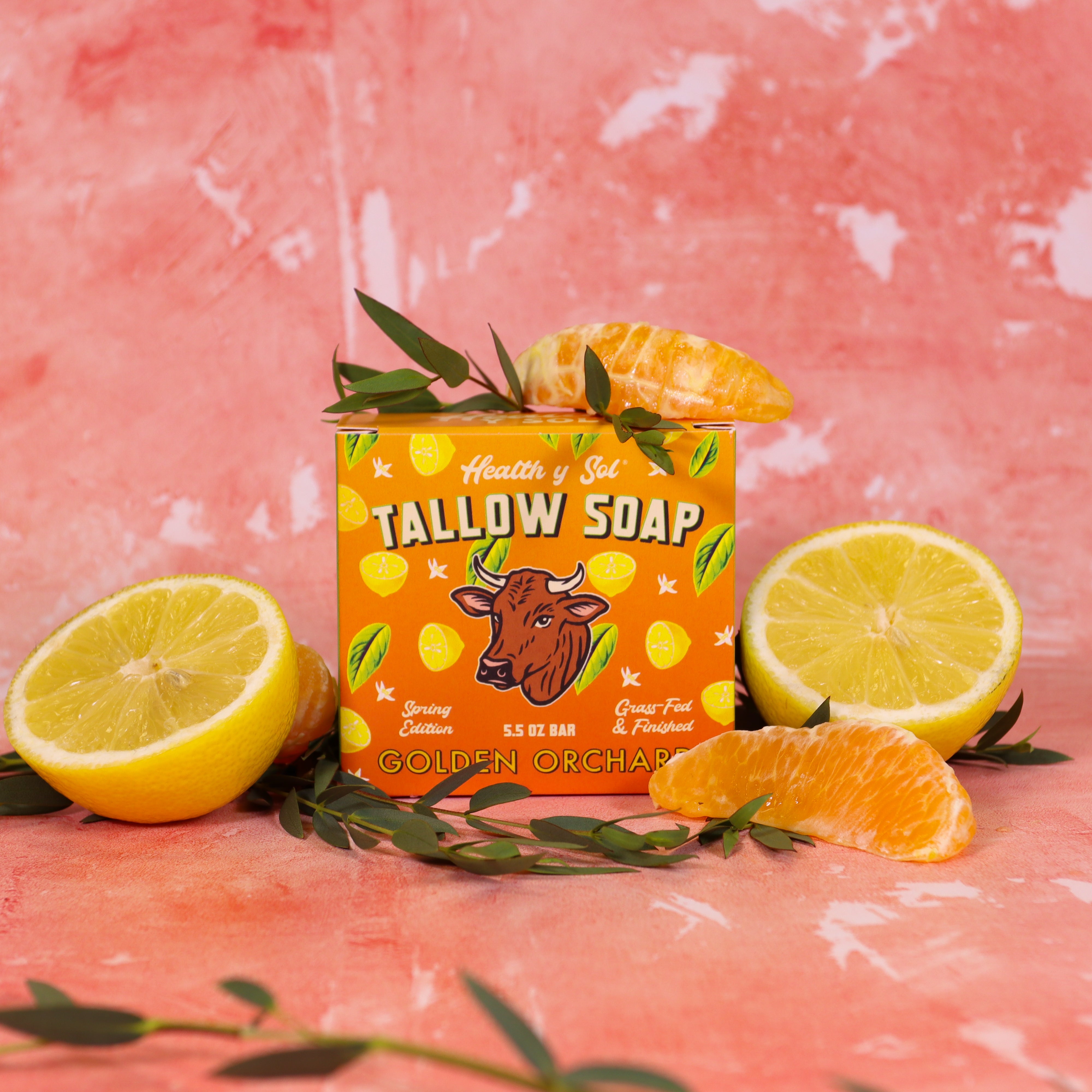 Tallow soap bar with lemon and orange slices on a pink background