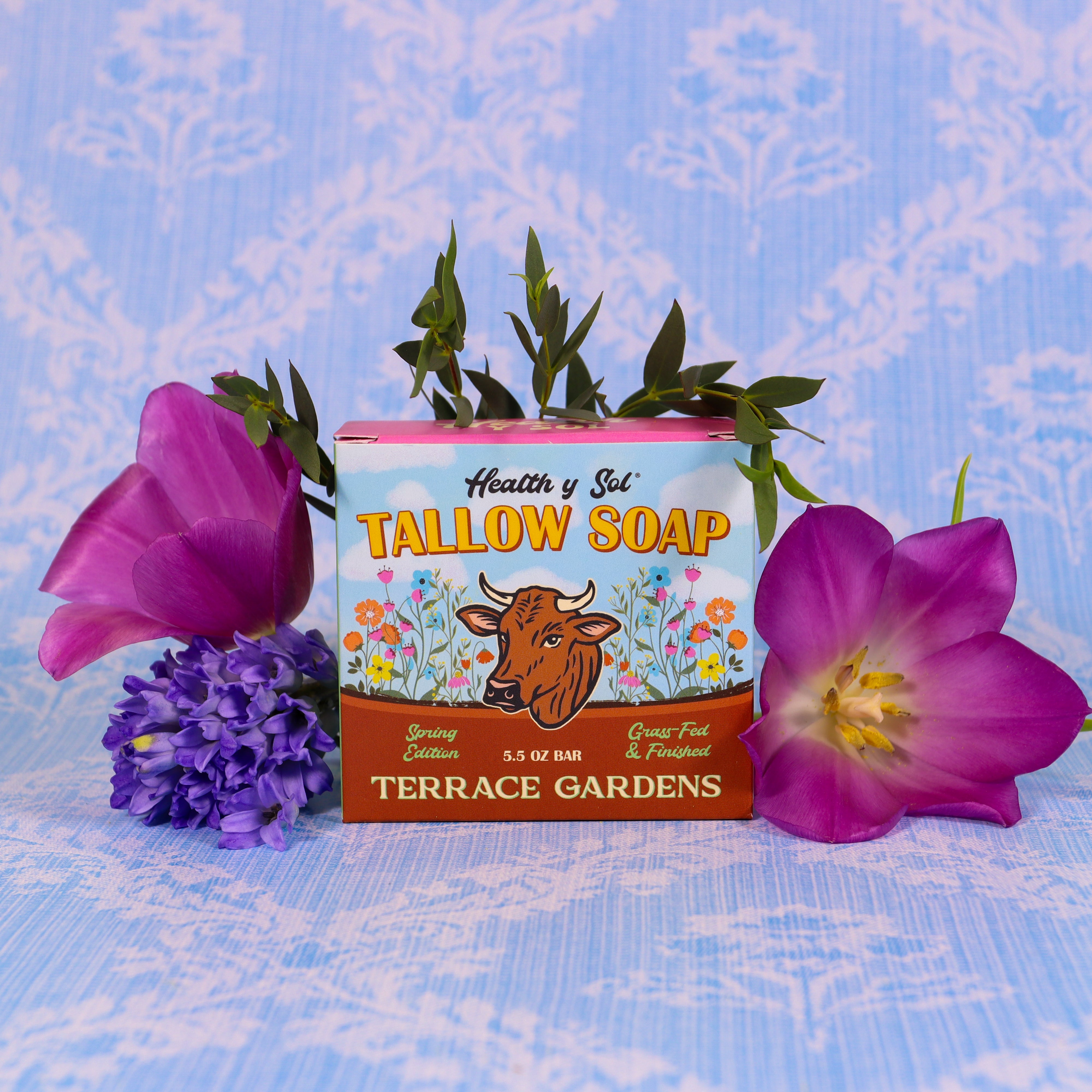 Tallow soap bar from Terrace Gardens with purple flowers on a blue patterned background